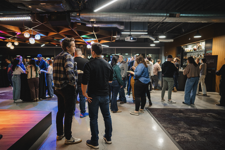 people standing in a crowded room with drinks and food